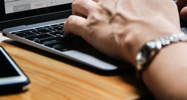 pessoa acessando notebook com smartphone ao lado para representar site mobile e site responsivo