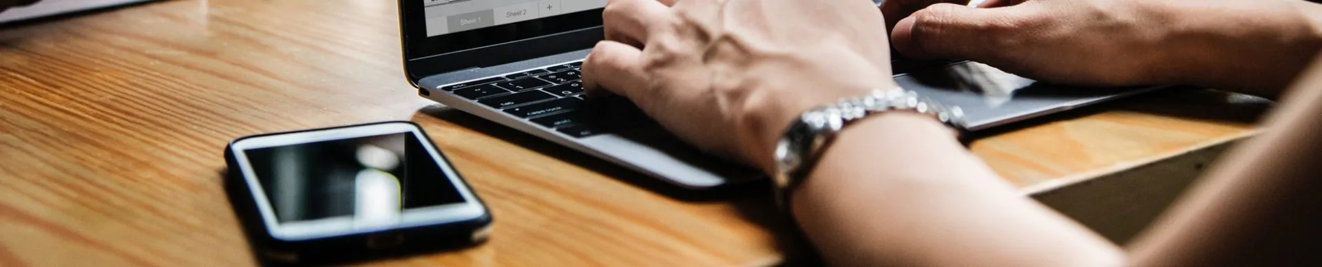 pessoa acessando notebook com smartphone ao lado para representar site mobile e site responsivo