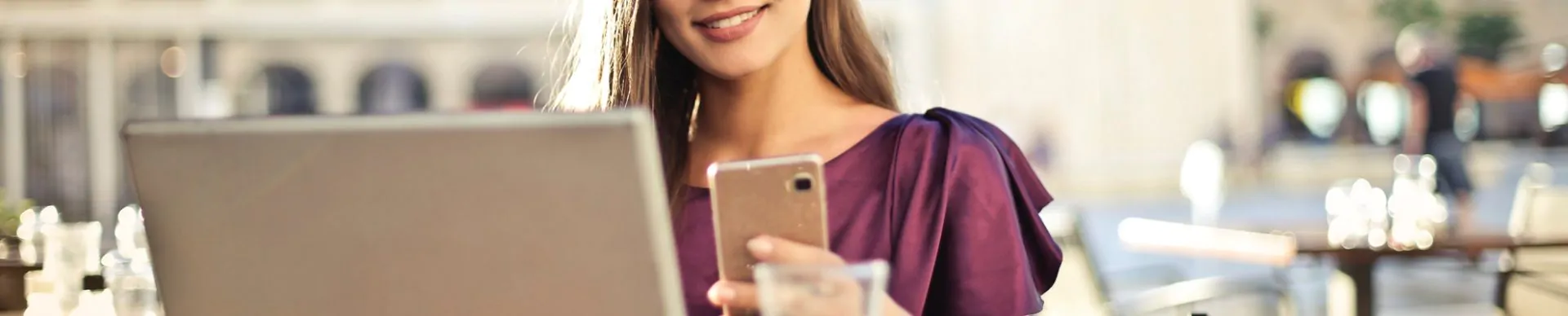 mulher acessando notebook com celular na mão pesquisando qual é melhor: weebly ou wordpress